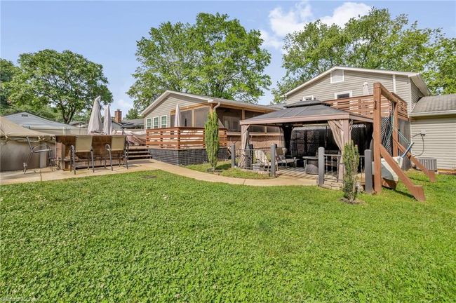 Outdoor living features spacious deck, large above ground pool with bar, and pergola with adjacent swing seating | Image 25