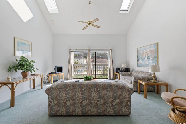Carpeted living area with a skylight, high vaulted ceiling, and a ceiling fan | Image 13