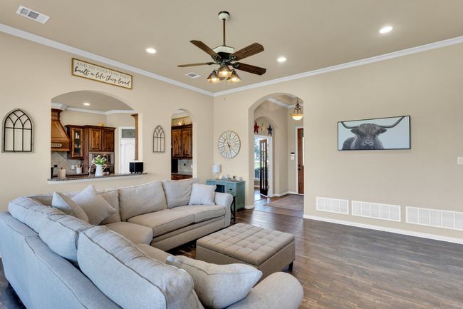 Living room with arched walkways, dark wood finished floors, recessed lighting, ceiling fan, and baseboards | Image 5