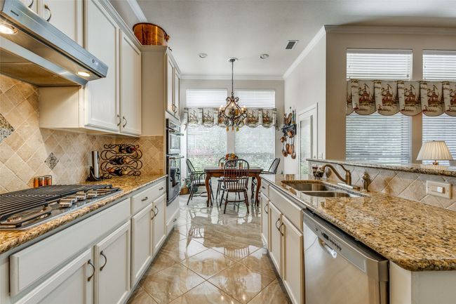 Kitchen with appliances with stainless steel finishes, extractor fan, decorative backsplash, crown molding, and a chandelier | Image 10