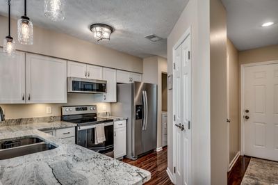 Kitchen featuring appliances with stainless steel finishes, light stone countertops, pendant lighting, and white cabinets | Image 3