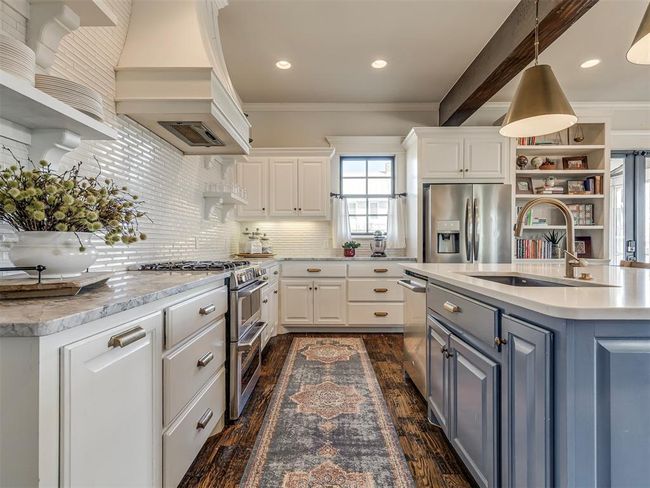 Kitchen with stainless steel appliances, premium range hood, white cabinetry, open shelves, and a sink | Image 8