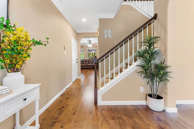 Entrance foyer featuring ornamental molding, ceiling fan, light wood-style floors, stairway, and baseboards | Image 5