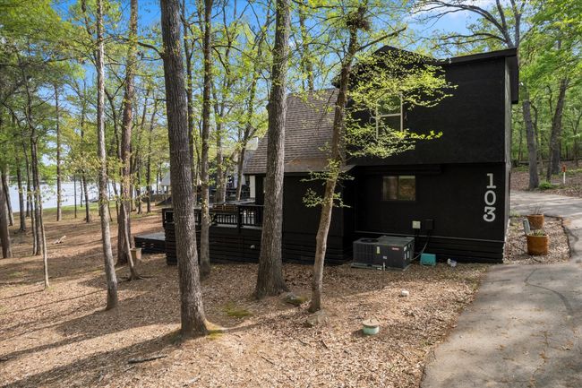 Rustic home featuring a deck with water view, a shingled roof, and central AC unit | Image 4