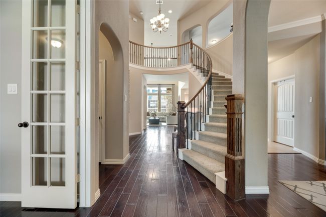 Entrance foyer featuring arched walkways, dark wood-style flooring, a chandelier, stairs, and a towering ceiling | Image 18