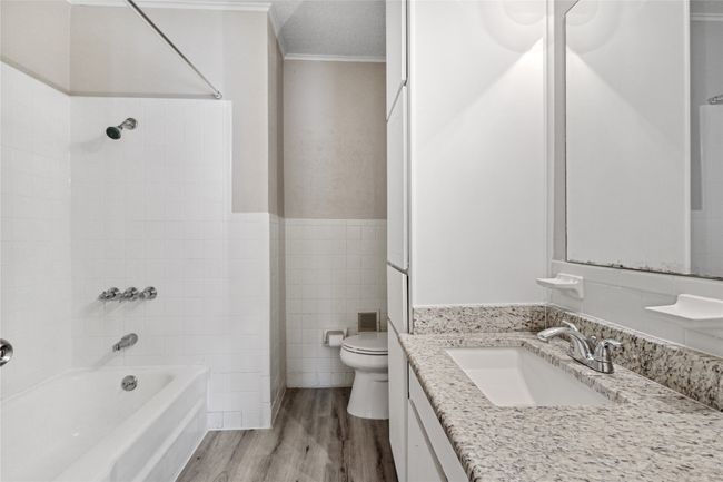 Full bathroom with crown molding, toilet, shower / washtub combination, tile walls, and wood finished floors | Image 19
