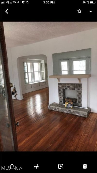 Unfurnished living room featuring a fireplace, dark wood-type flooring, and a textured ceiling | Image 2