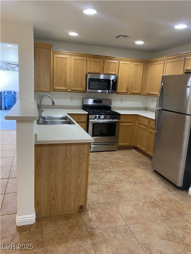 Kitchen with a sink, visible vents, a peninsula, light countertops, and appliances with stainless steel finishes | Image 22