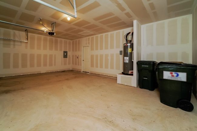 Garage with electric water heater, electric panel, and a garage door opener | Image 23