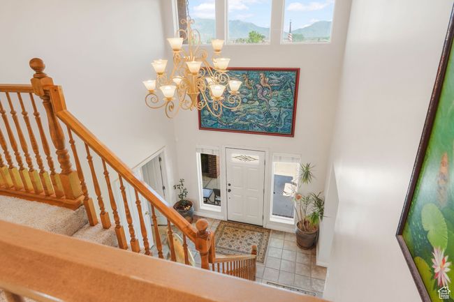 Foyer entrance featuring tile patterned flooring, a chandelier, baseboards, stairway, and a towering ceiling | Image 16