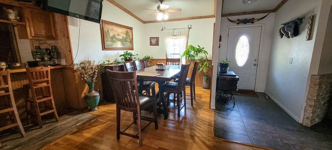 Dining space with ceiling fan, wood flooring. Main entryway and foyer to the right. | Image 12