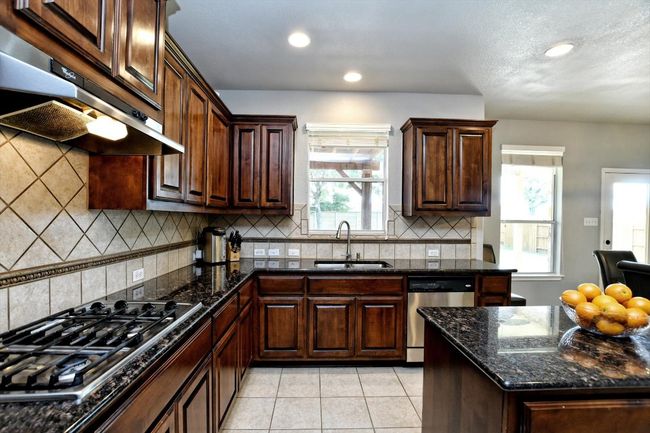Kitchen featuring a sink, under cabinet range hood, stainless steel appliances, recessed lighting, and light tile patterned floors | Image 12