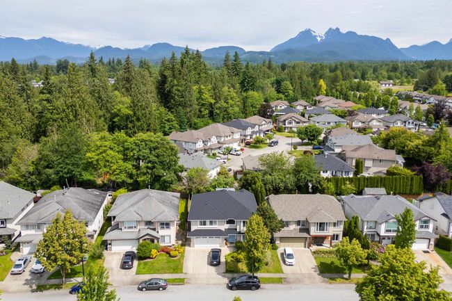 Aerial view of residential area featuring a mountain backdrop and a heavily wooded area | Image 32