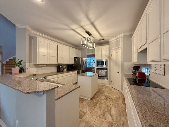 Kitchen featuring a sink, appliances with stainless steel finishes, light stone countertops, and tasteful backsplash | Image 10