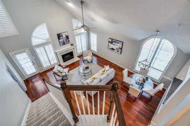 Living room with a textured ceiling, a fireplace, ceiling fan, wood finished floors, and high vaulted ceiling | Image 17