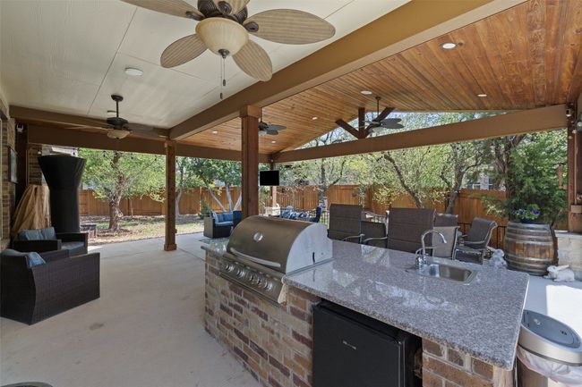 Built-in outdoor kitchen with gas grill, sink, and fridge perfect for dining al fresco | Image 27