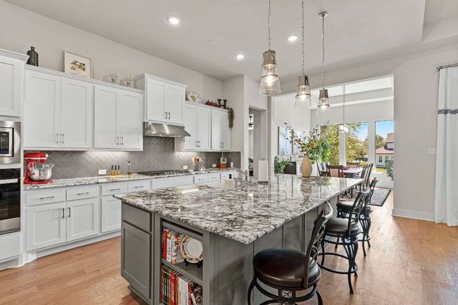 Kitchen with a kitchen island with sink, pendant lighting, and white cabinetry | Image 17