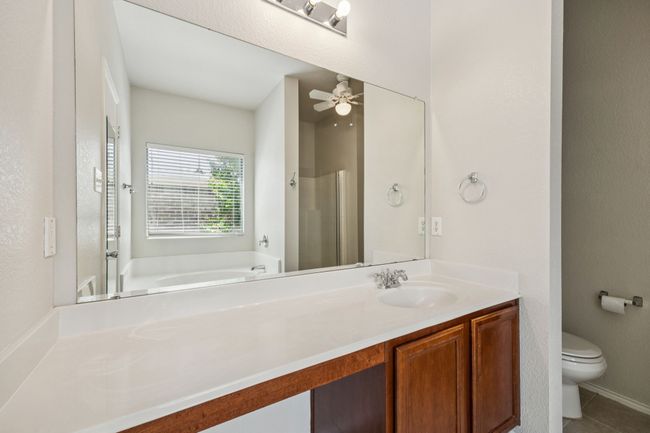 Bathroom featuring a bath, vanity, ceiling fan, a shower, and tile patterned floors | Image 17