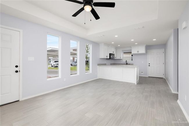 Unfurnished living room featuring a sink, baseboards, a ceiling fan, recessed lighting, and light wood-style floors | Image 4