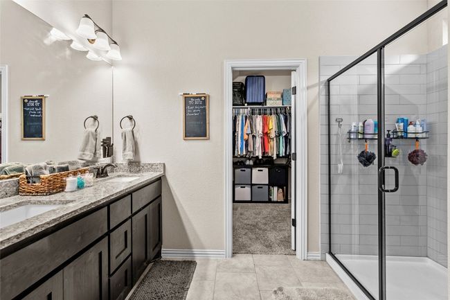 Bathroom featuring double vanity, a shower stall, tile patterned floors, and a walk in closet | Image 16