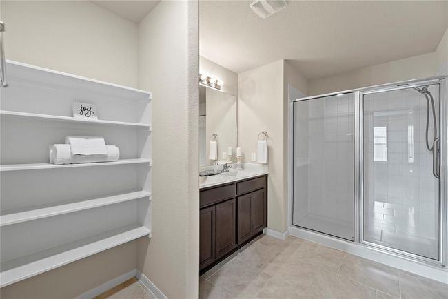 The expansive walk-in shower, adorned with stunning tile work and a sleek glass front, offers a luxurious escape for a quick rinse or a refreshing retreat. The additonal built-in shelving ensures a place for everything. | Image 15