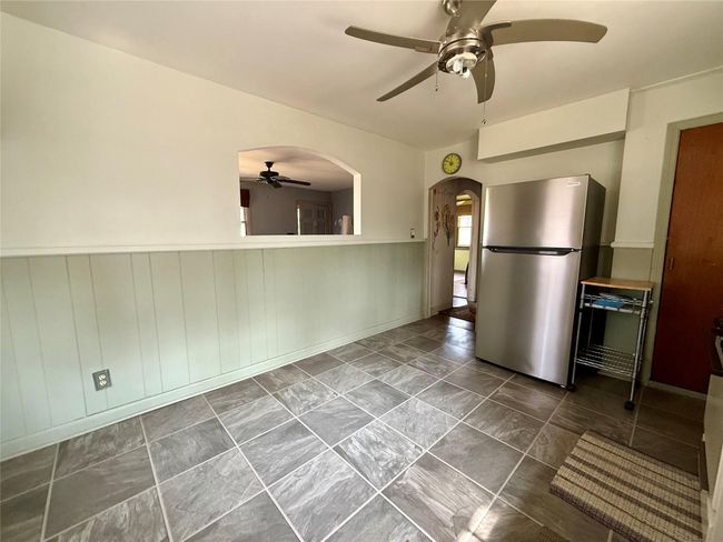 Kitchen with a wainscoted wall, a ceiling fan, arched walkways, and freestanding refrigerator | Image 14