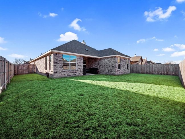 Back of property featuring roof with shingles, a yard, brick siding, a fenced backyard, and a chimney | Image 25