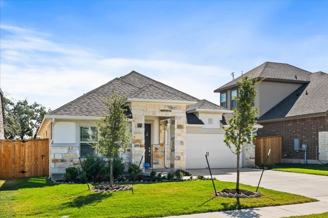 Contemporary home featuring fence, a front yard, a garage, stone siding, and driveway | Image 33