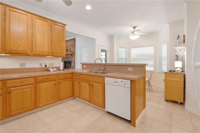 Kitchen with a peninsula, a ceiling fan, light tile patterned flooring, dishwasher, and a sink | Image 15
