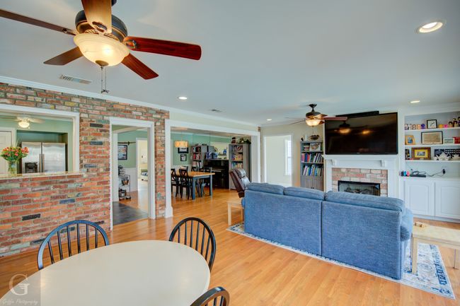 Dining space with brick wall, light wood-type flooring, a fireplace, and visible vents | Image 10