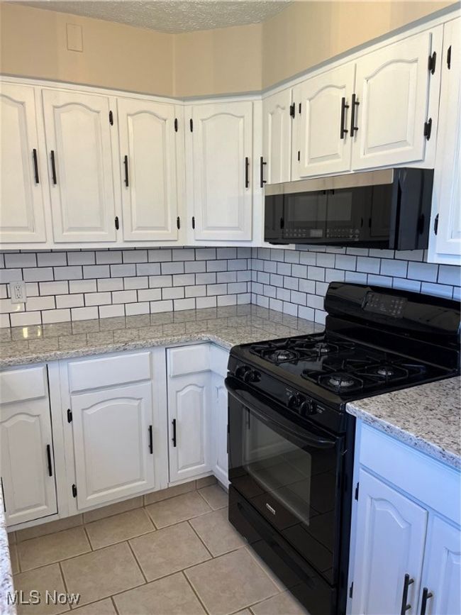 Kitchen featuring decorative backsplash, white cabinets, range. | Image 8