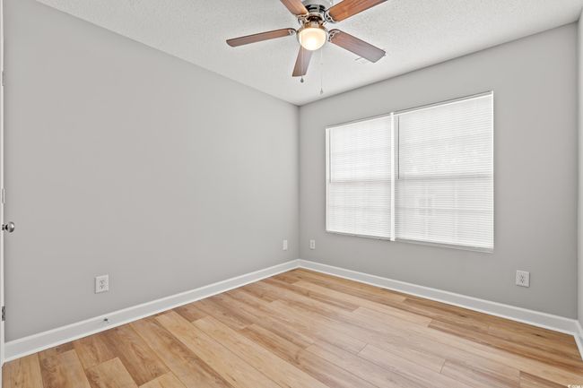 Empty room with a ceiling fan, light wood-style flooring, and a textured ceiling | Image 19