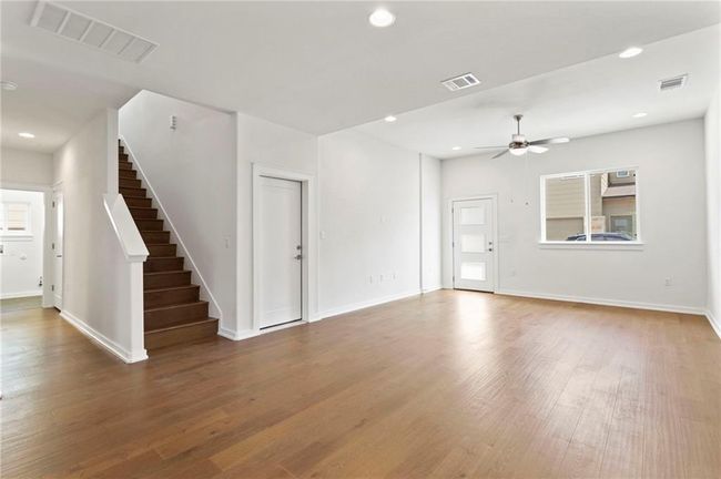Unfurnished living room with wood finished floors, a ceiling fan, stairway, and recessed lighting | Image 16