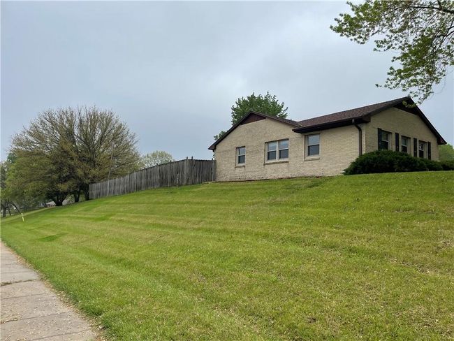 View of home's exterior with brick siding, a lawn, and fence | Image 5
