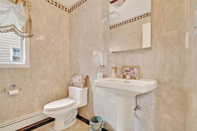 Bathroom with a baseboard heating unit, tile walls, and toilet | Image 25