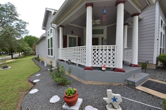 View of side of home with covered porch, a yard, and a ceiling fan | Image 5
