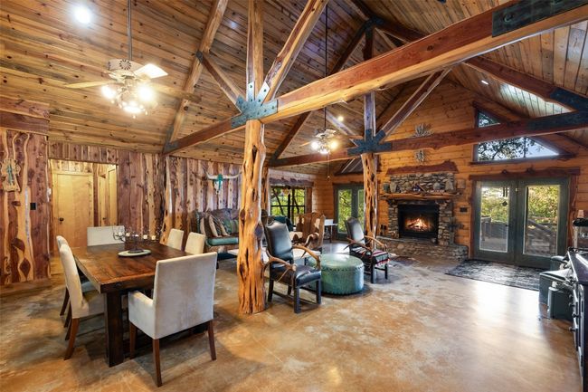 Dining area featuring a ceiling fan, wooden walls, concrete floors, plenty of natural light, and a wood ceiling with exposed beams | Image 19