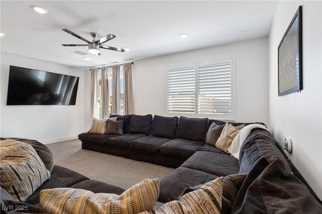 Carpeted living area with a healthy amount of sunlight, ceiling fan, visible vents, and baseboards. Some personal property items removed virtually for picture. | Image 14