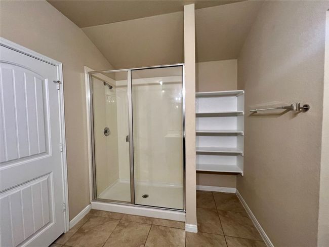 Primary bathroom with a shower stall, tile patterned flooring, baseboards, and lofted ceiling | Image 16