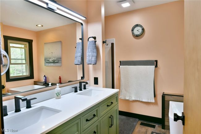 Bathroom featuring a tub, double vanity, wood finished floors, and baseboards | Image 29