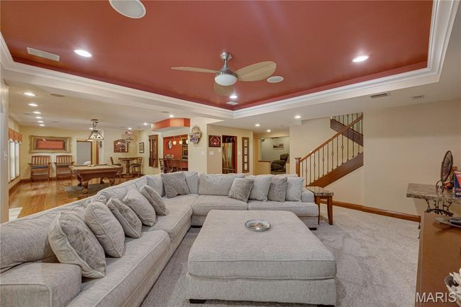 Living room with a tray ceiling, ornamental molding, recessed lighting, a ceiling fan, and stairway | Image 60