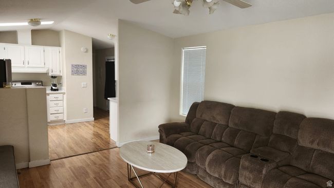 Living area featuring ceiling fan, vaulted ceiling, light wood-style floors, and baseboards | Image 10