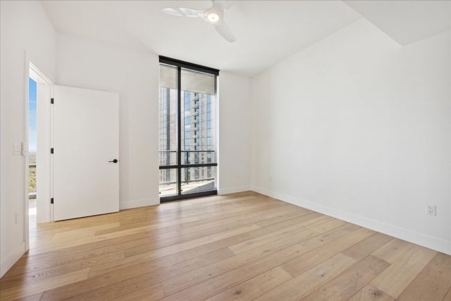 Unfurnished room with a wall of windows, light wood-style floors, and a ceiling fan | Image 9