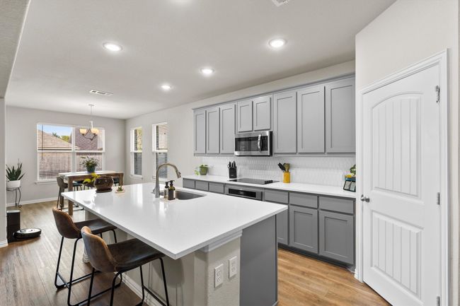 Kitchen with gray cabinetry, a center island with sink, backsplash, a breakfast bar area, and light countertops | Image 14
