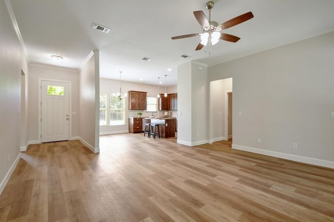 Unfurnished living room featuring crown molding, light wood finished floors, ceiling fan, and a chandelier | Image 6
