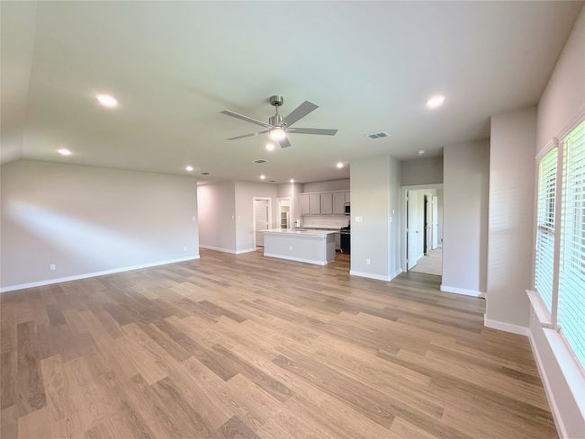 Unfurnished living room with a ceiling fan, light wood-type flooring, baseboards, and recessed lighting | Image 9