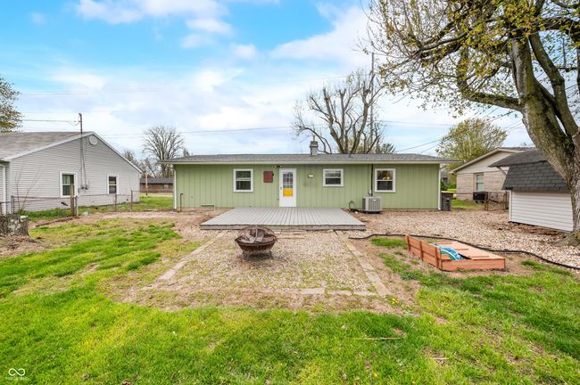 rear view of house featuring central AC unit, fence, a lawn, a fire pit, and a deck | Image 6