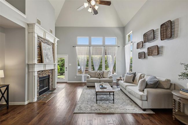 Living room with high vaulted ceiling, dark hardwood / wood-style flooring, ceiling fan, and a stone fireplace | Image 10