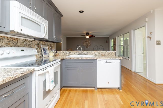 Kitchen featuring white appliances, gray cabinetry, a peninsula, light wood-style floors, and a ceiling fan | Image 14