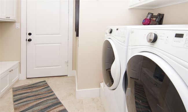 Laundry room featuring washer and clothes dryer, cabinet space, and light tile patterned floors | Image 23